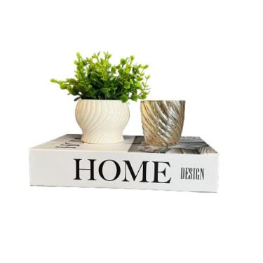 Imagem de Livro de papelão, vaso branco cerâmico e castiçal de vidro