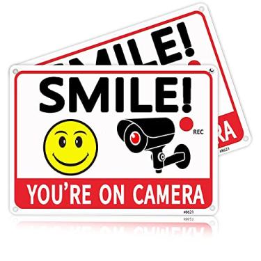 Imagem de Pacote com 2 placas Smile You're On Camera – Alumínio, tinta UV, placas de vigilância por vídeo ao ar livre e câmeras de segurança para propriedade – Laranja com fonte preta, 18 x 25 cm, 4 furos pré-perfurados – Placas de segurança doméstica ideais para quintal, negócios, alerta de entrada de automó