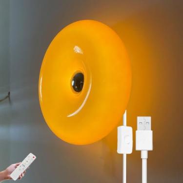 Imagem de Luminária de parede em formato de donut com LED laranja, controle remoto e interruptor no cabo. Possui porta USB para carregamento e função timer. Ideal para cabeceiras. A luminária é dimeri