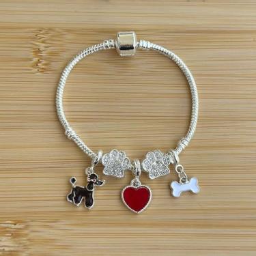 Imagem de Pulseira com 5 berloques: cachorrinho poodle preto, separador patinha de brilhos, ossinho e coração vermelho - banhado a prata